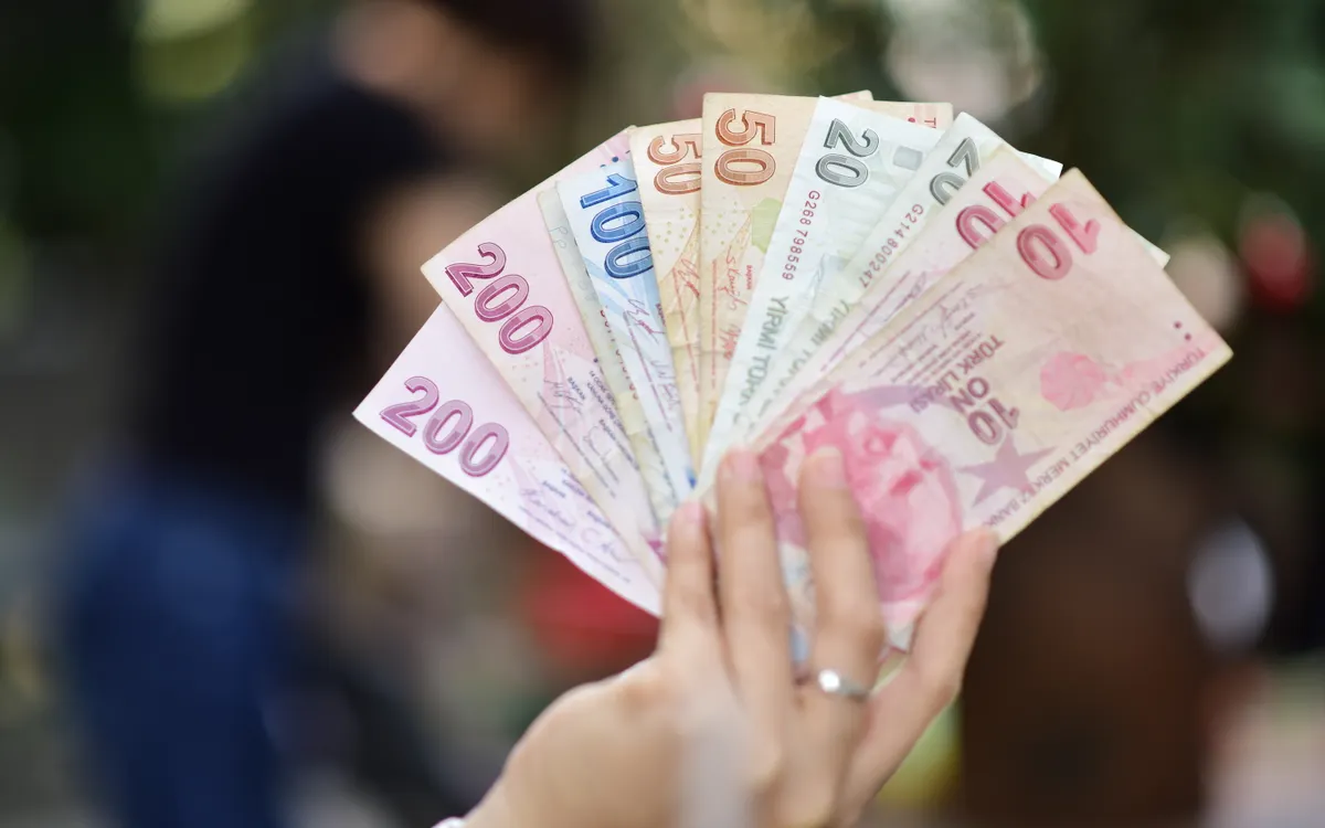 A hand holding Turkish lira banknotes in Istanbul