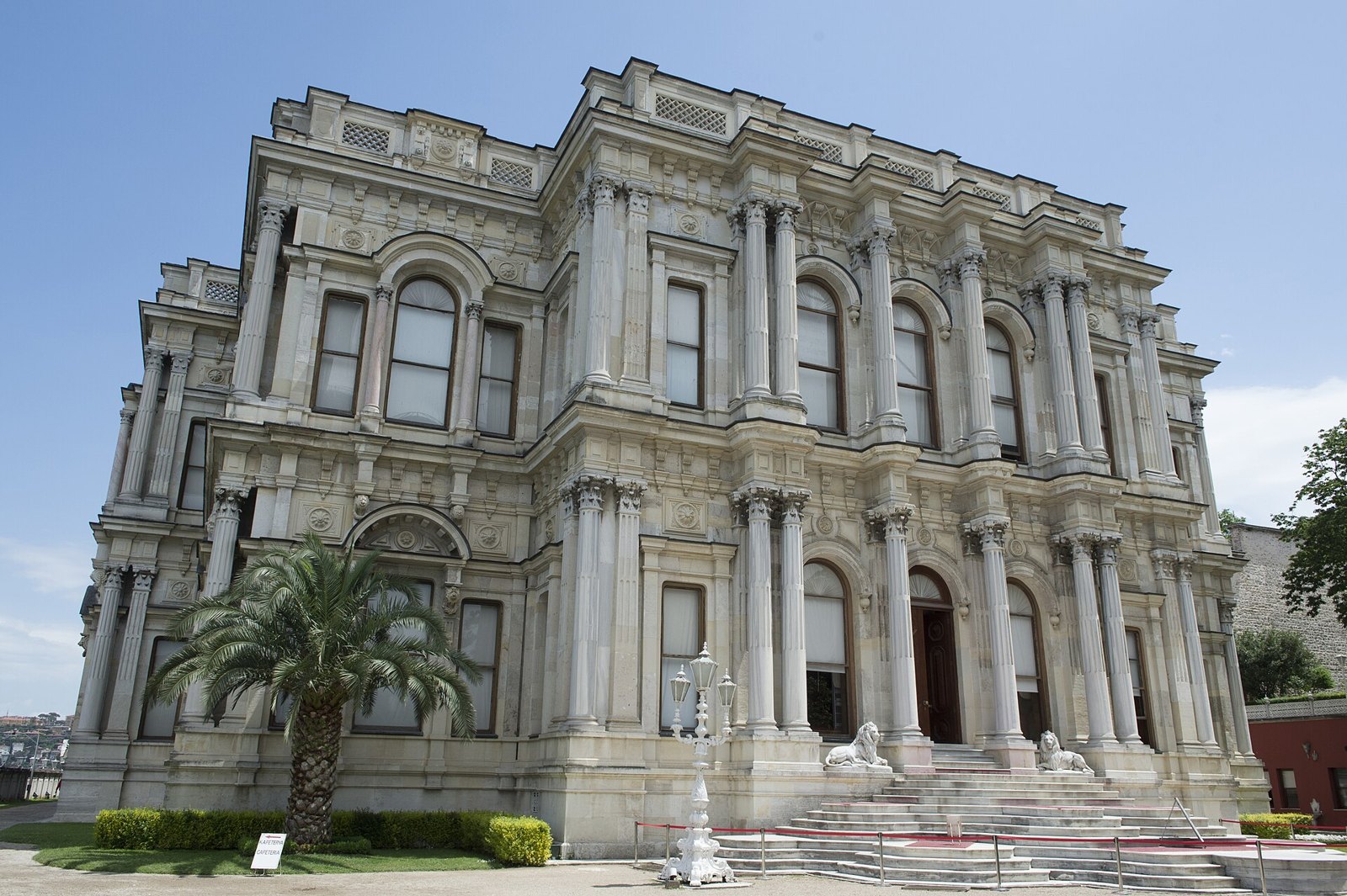 White stone front of Beylerbeyi Palace with columns, arched windows and a palm tree