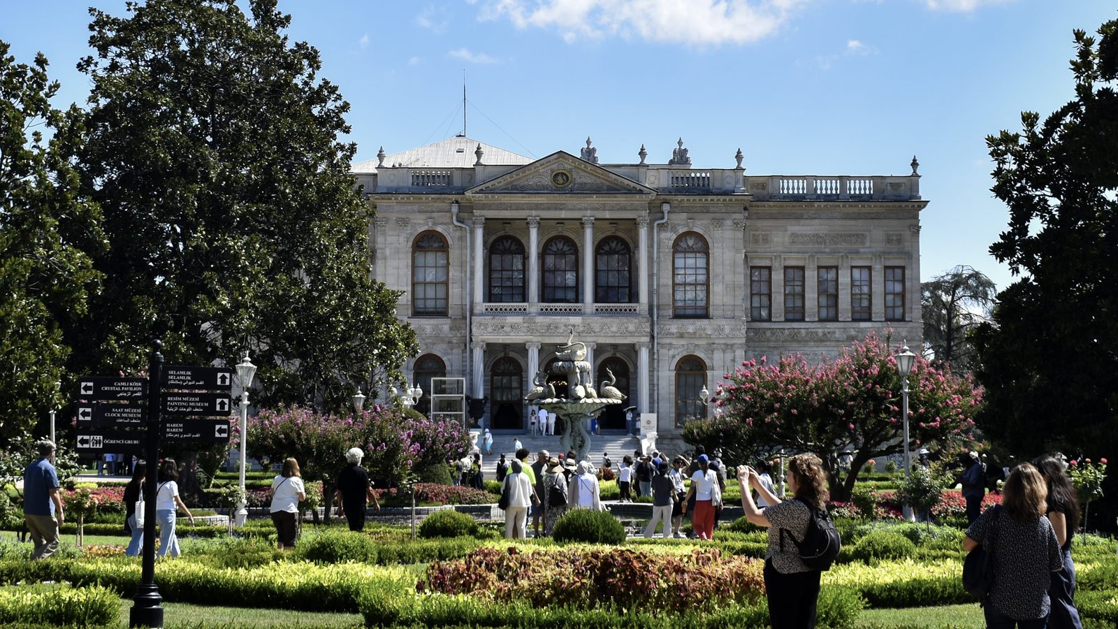 Visitors in the formal garden in front of Dolmabahçe Palace on a sunny day