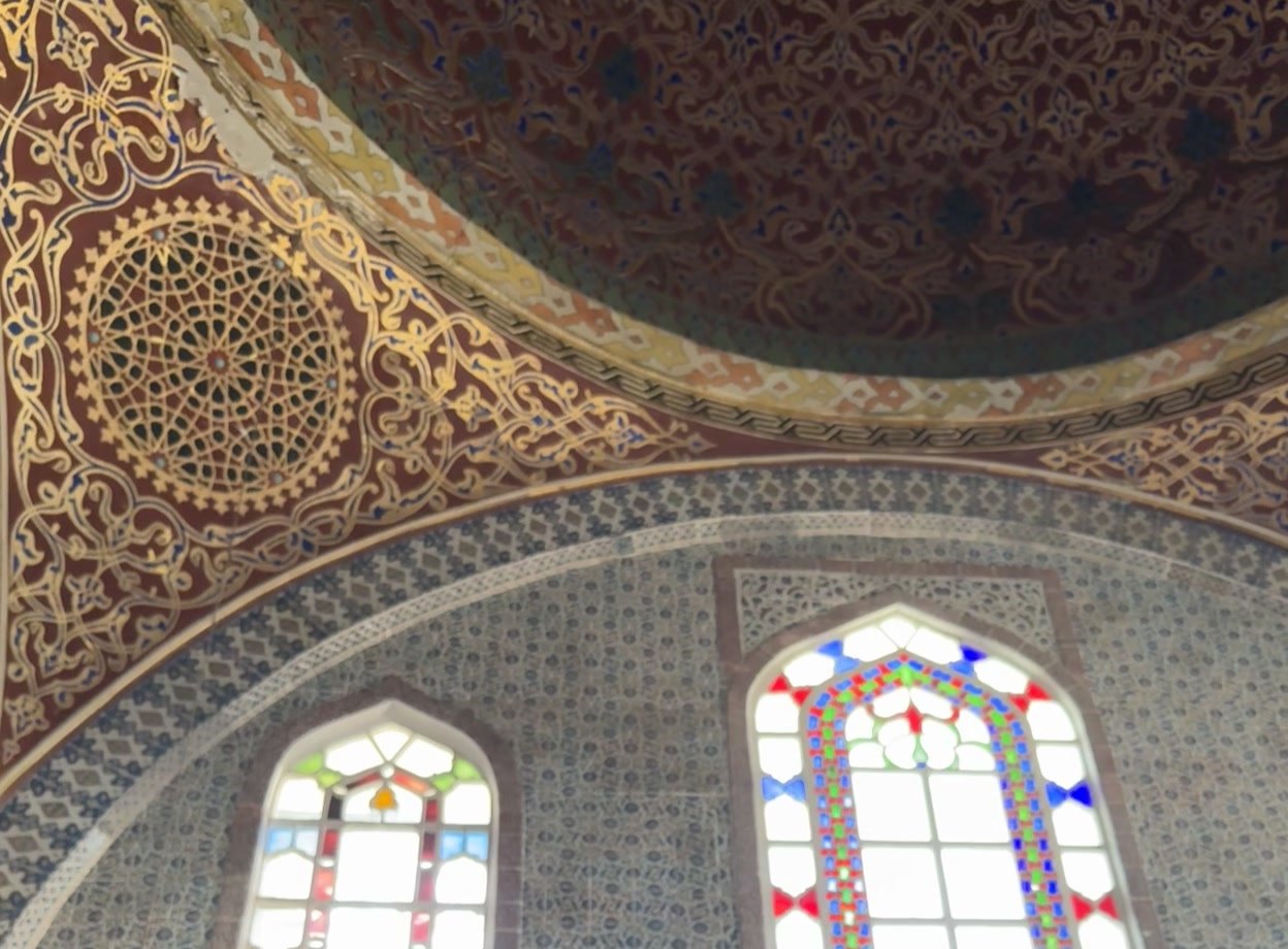 Stained-glass windows above a band of blue-and-white calligraphy tiles in the Topkapı Harem