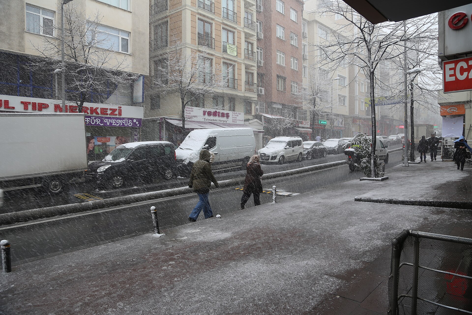 Pedestrians and parked trucks on a snowy street in Istanbul
