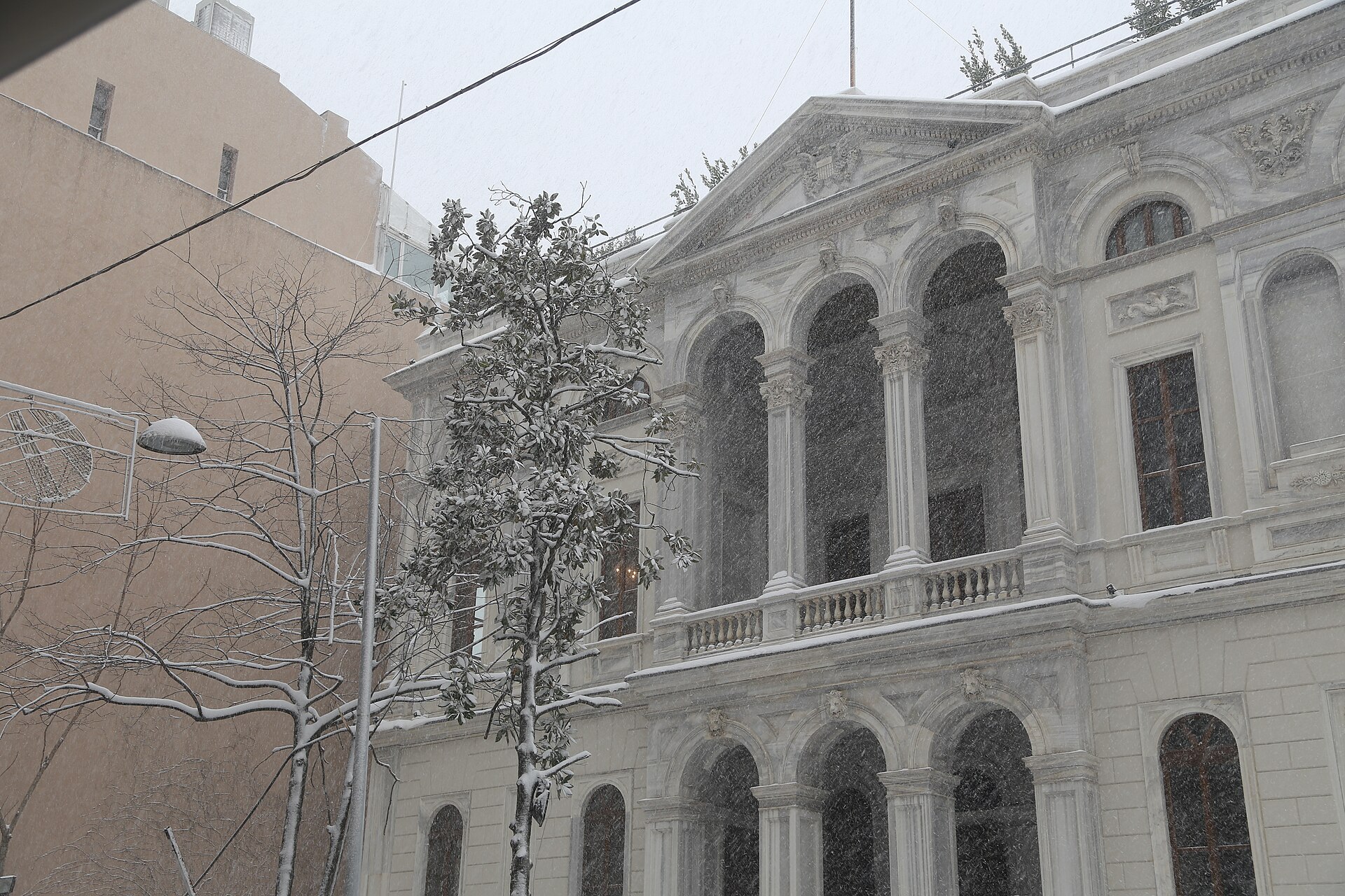 A neoclassical building and bare trees dusted with snow in Istanbul