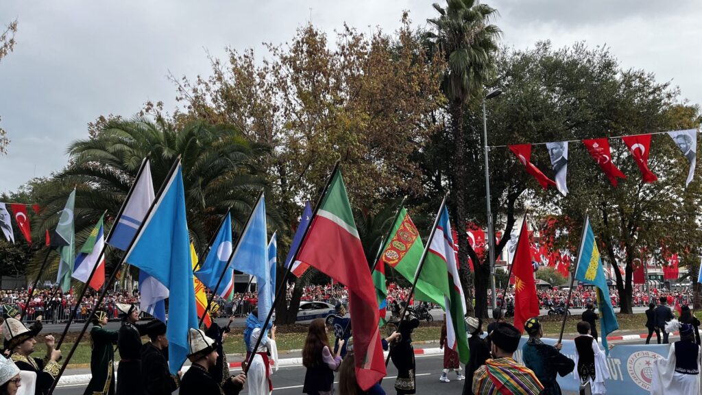 Flag bearers in traditional costume at the Republic Day parade in Istanbul under strings of Turkish flags