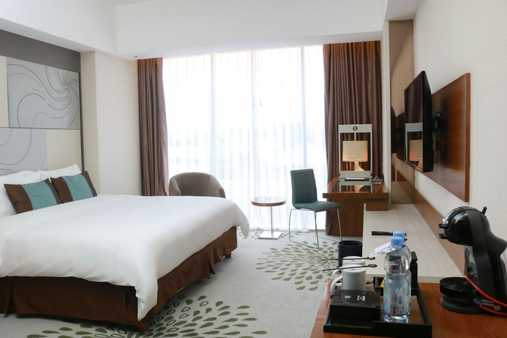 Illustrative hotel bedroom with a double bed, desk and large window