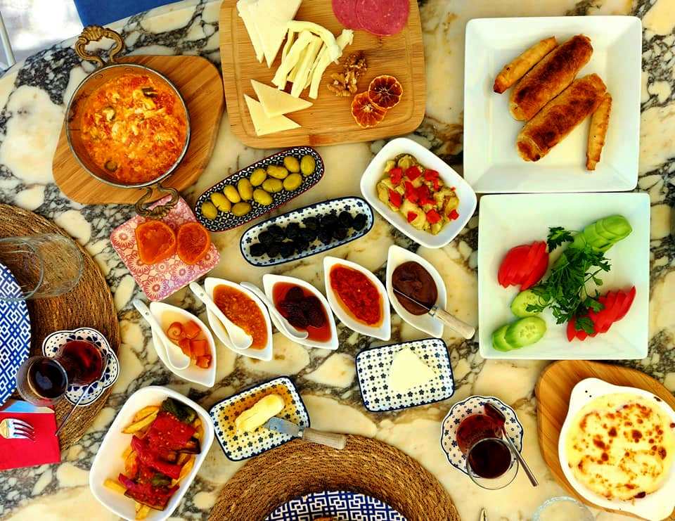 A Turkish breakfast spread with olives, cheeses, tomatoes, jams, sausages and a glass of tea on a table