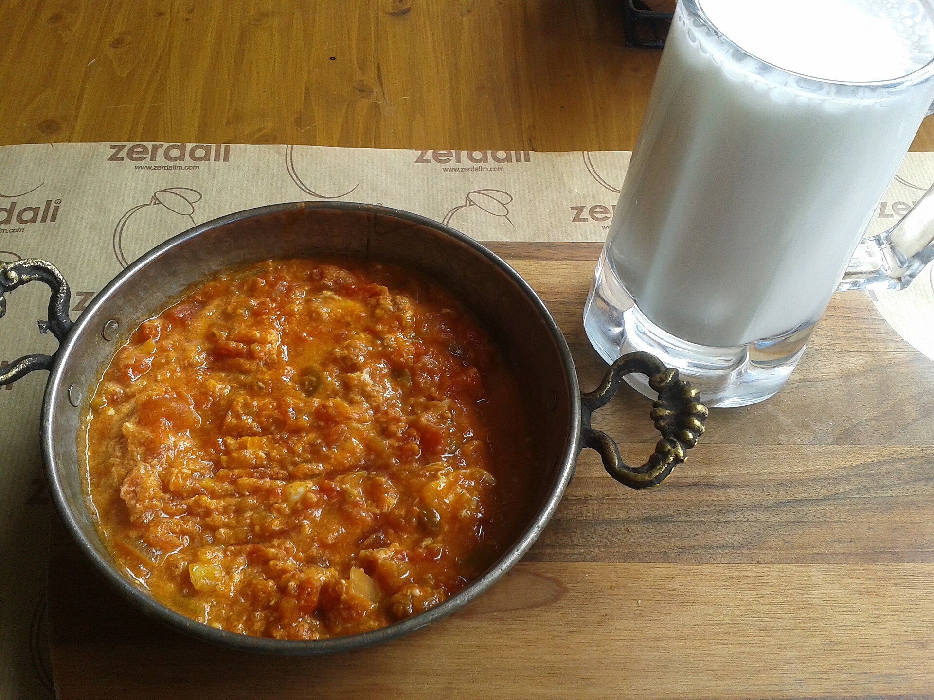 A pan of menemen, a Turkish breakfast dish of eggs, tomatoes and peppers, served with a glass of ayran