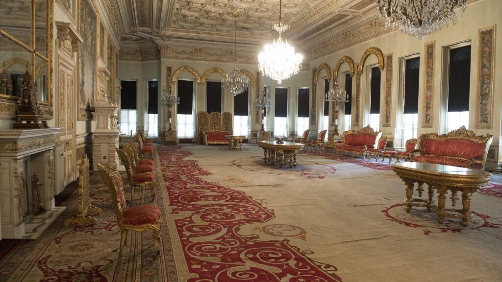 Ornate hall with chandeliers, gilded furniture and a large carpet in Yıldız Palace